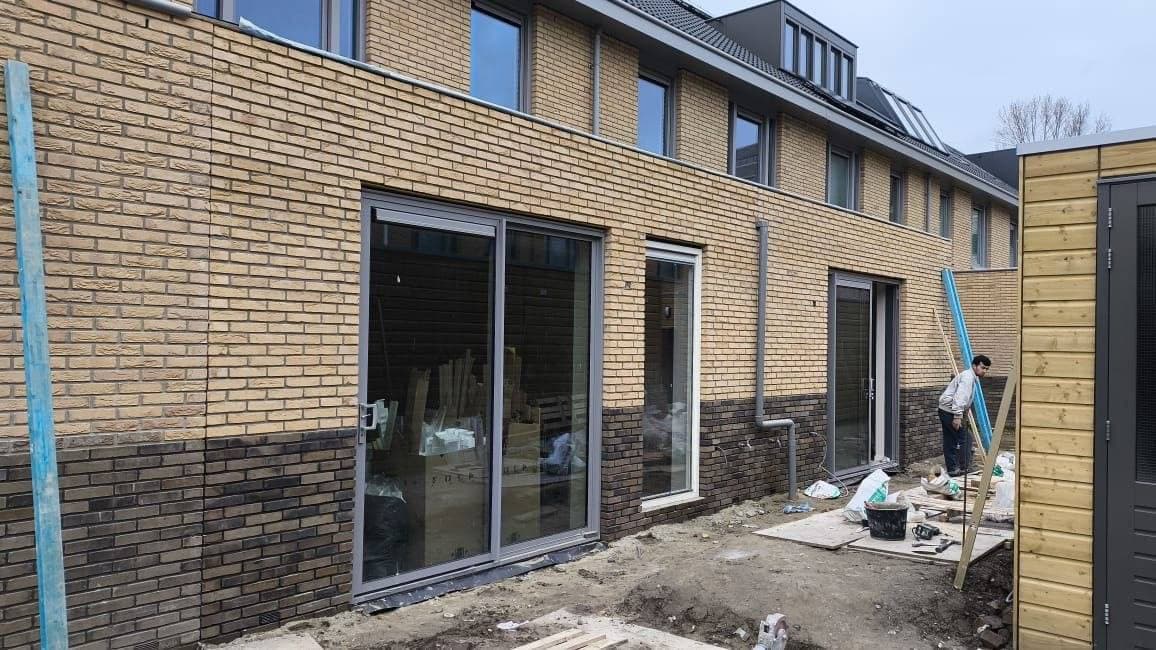 Nieuw metselwerk met schuifpui aan de achtergevel van een woning in aanbouw